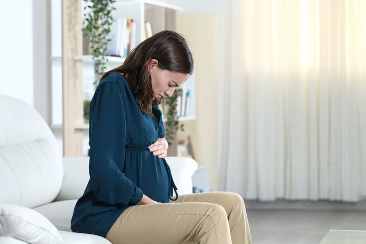 A pregnant person sitting on a couch

AI-generated content may be incorrect.